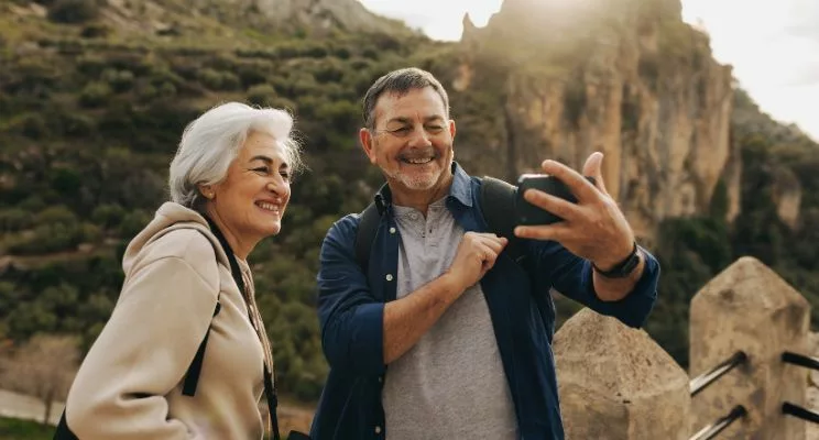 elderly couple taking a selfie in front of a mountain