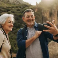 elderly couple taking a selfie in front of a mountain